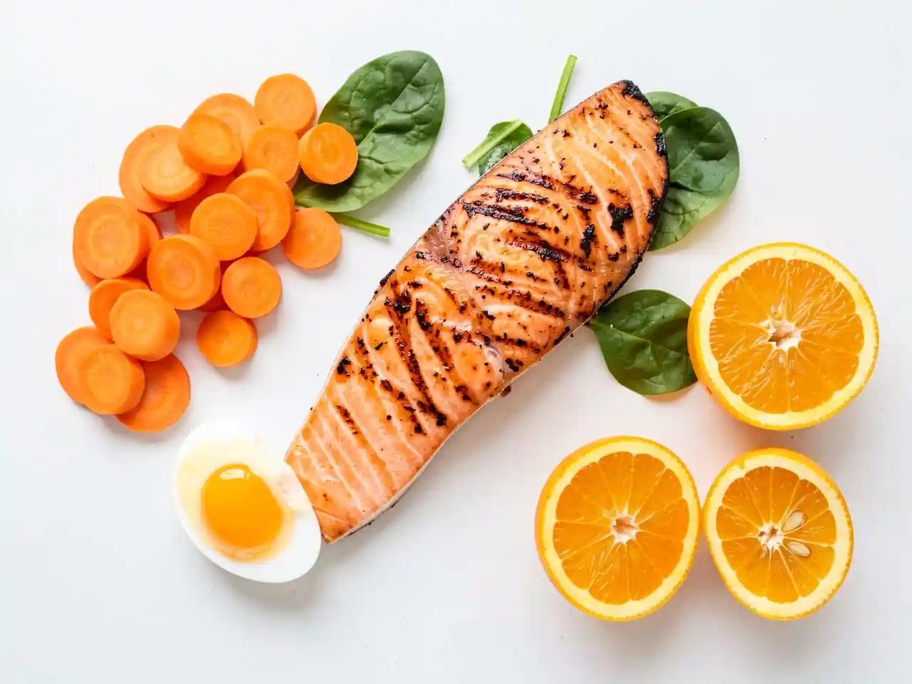 Colorful flatlay of carrots, salmon, spinach, egg, and citrus for eye health