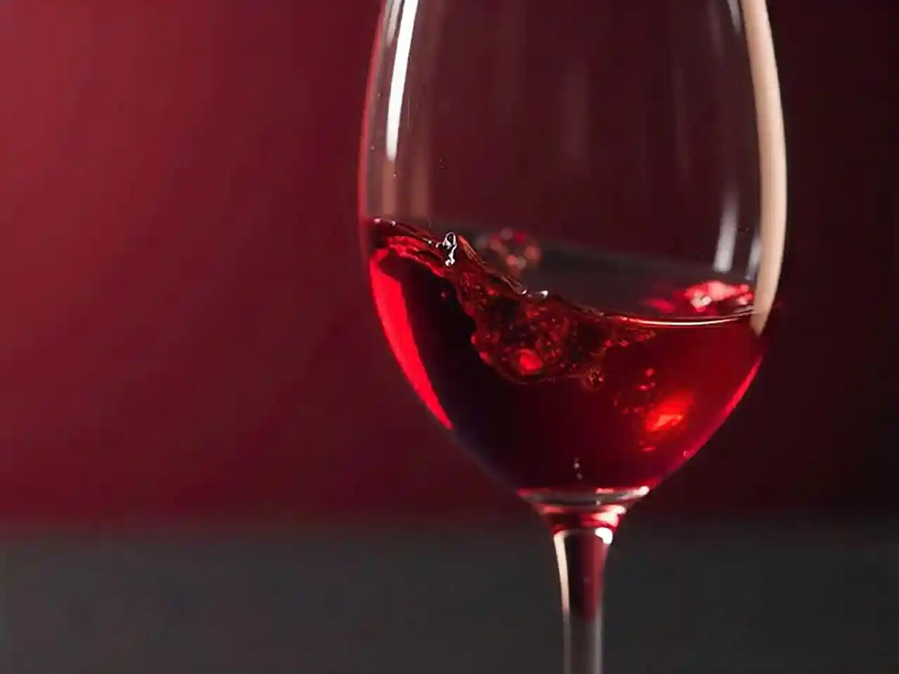 swirling red wine in clear glass on wooden table