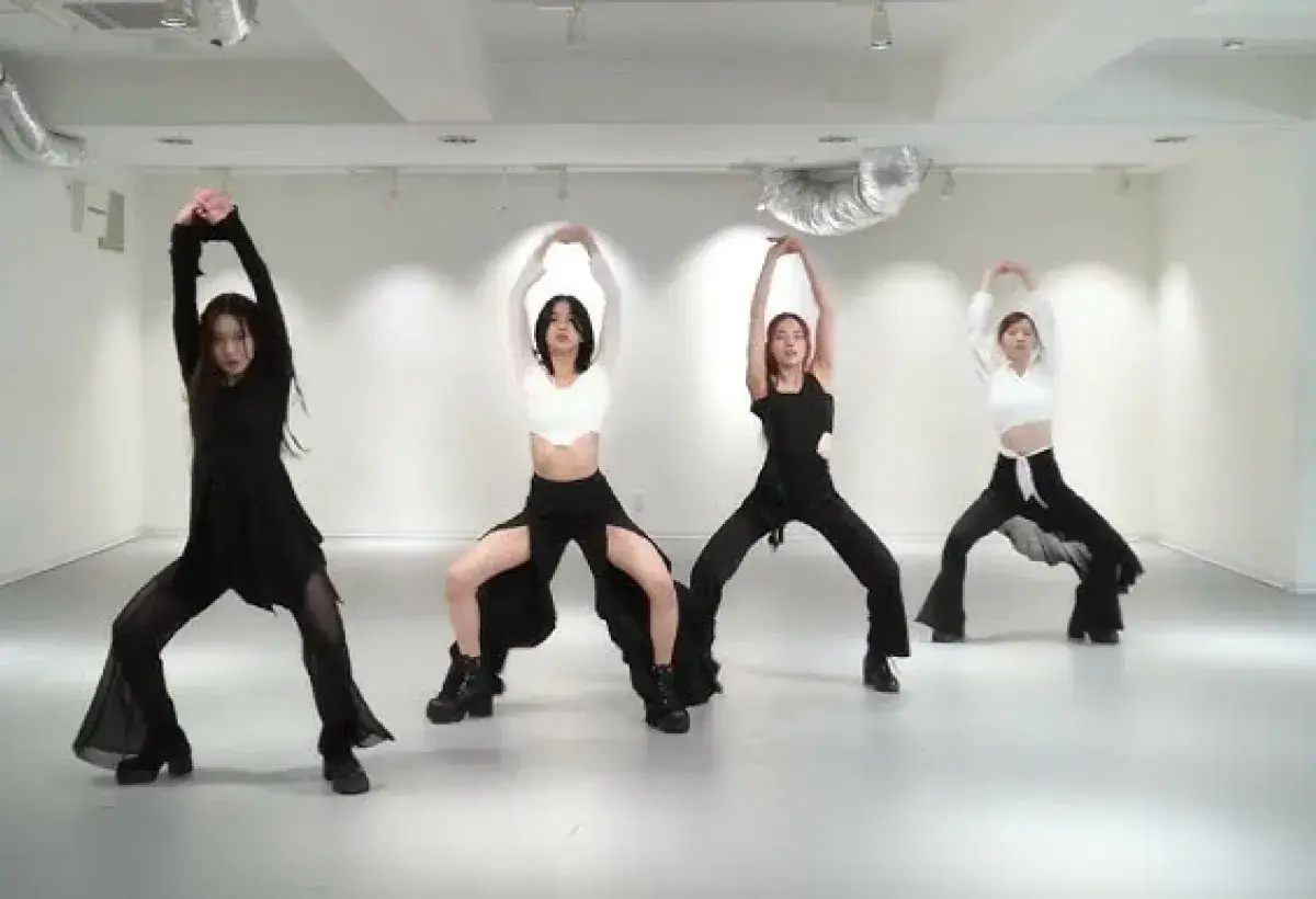 K-pop group rehearsing dance routine in mirrored studio