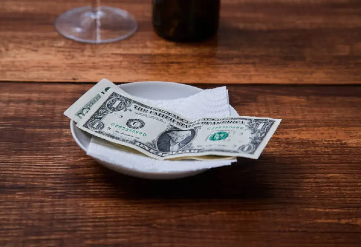 Customer leaving a cash tip for restaurant staff in the US.