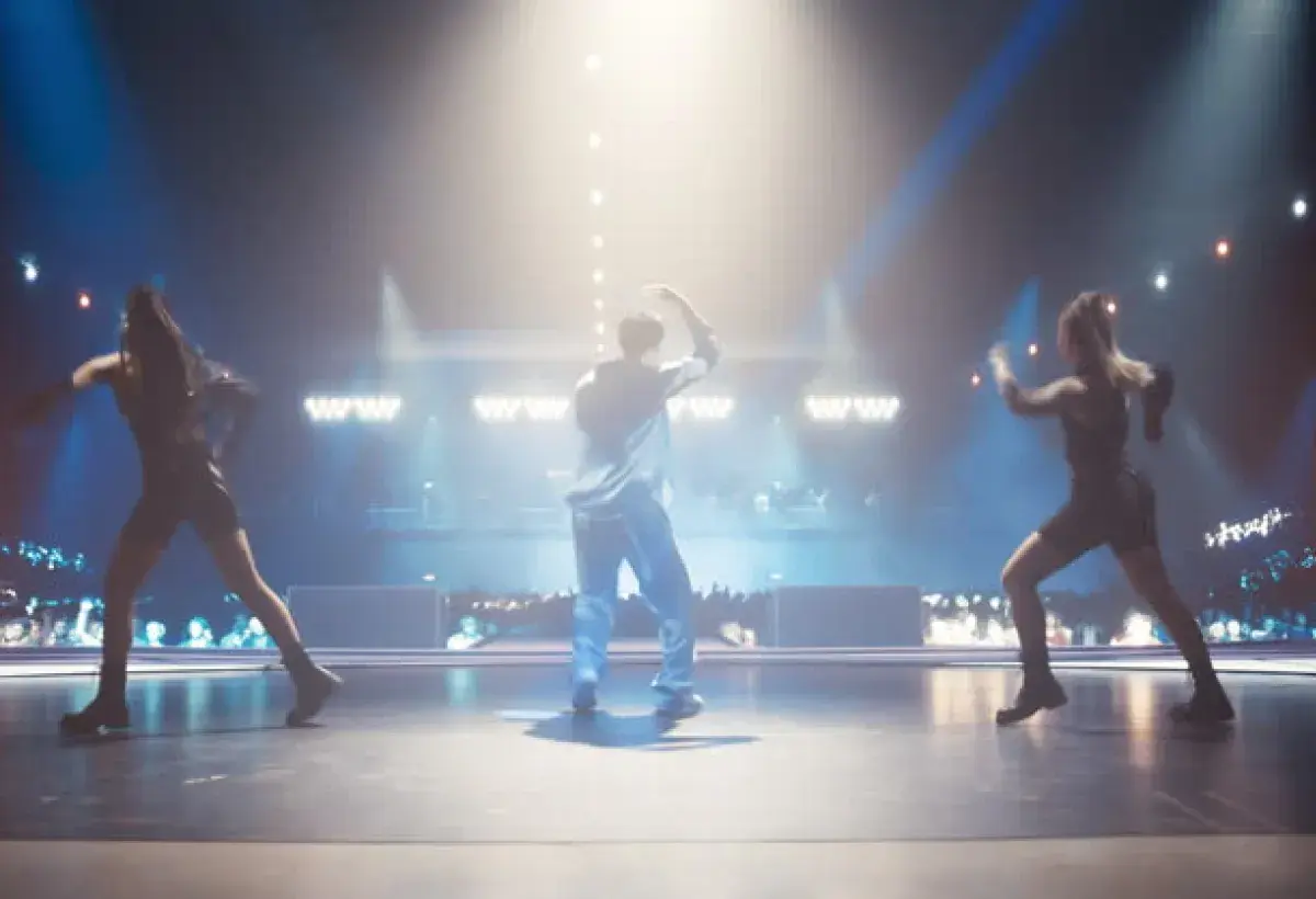 K-pop idols performing synchronized choreography on stage under colorful lights
