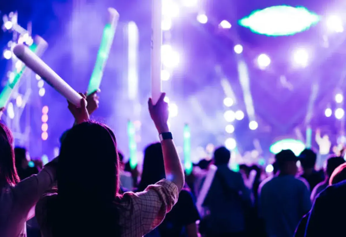 K-pop fans holding official lightsticks and banners at a live concert