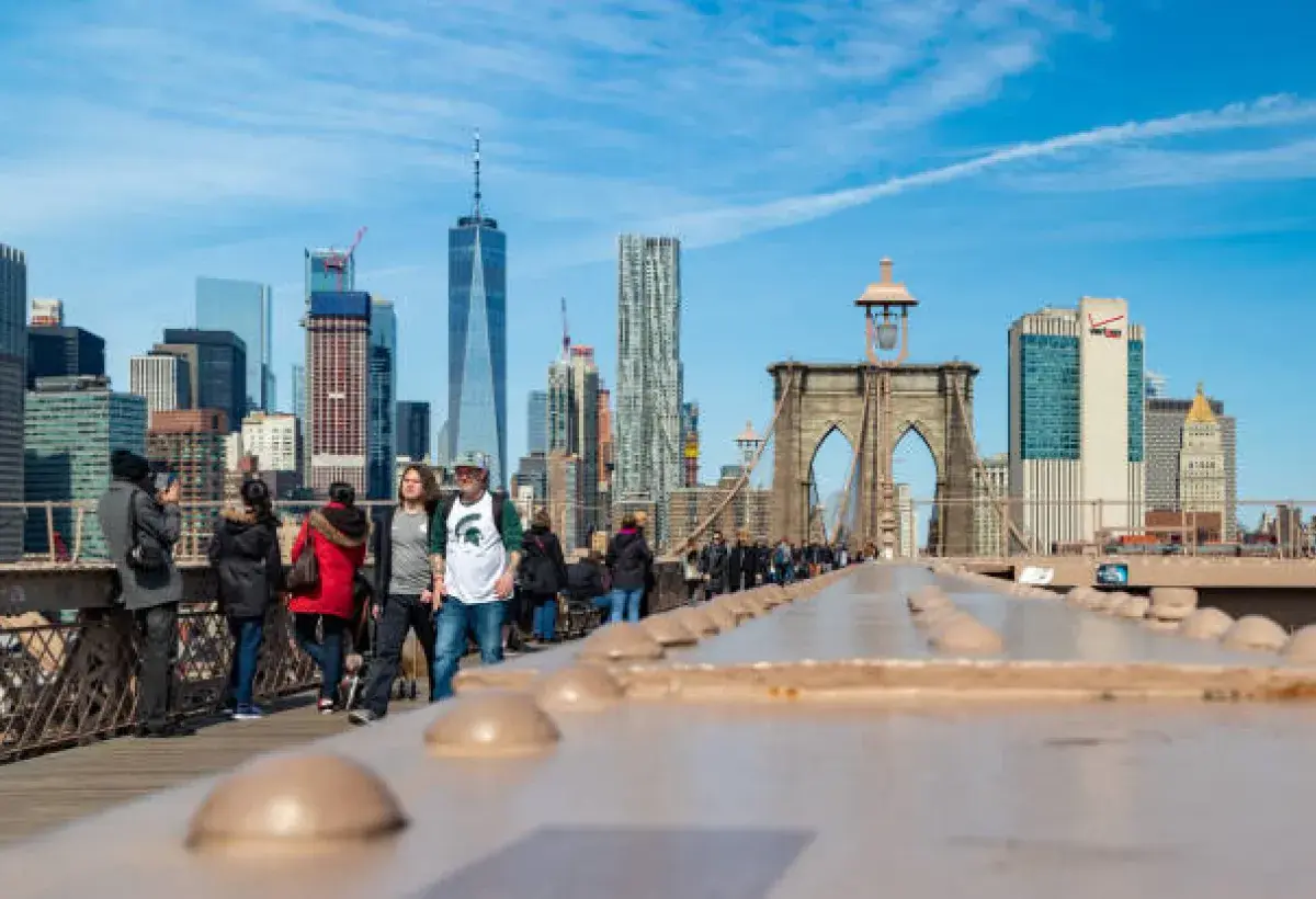 People walking on Brooklyn Bridge with city skyline in the background