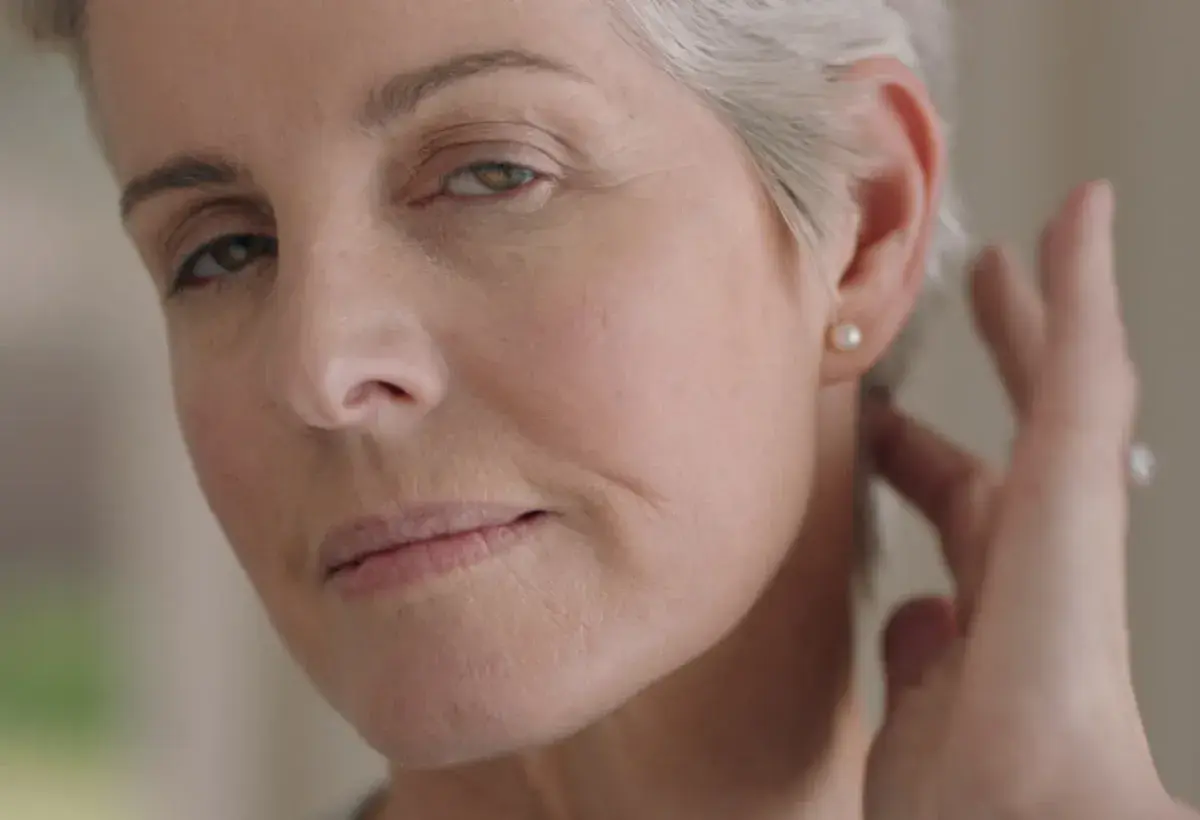 portrait beautiful mature woman looking in mirror at perfect healthy skin touching face with hands enjoying smooth natural complexion with anti aging skincare getting ready at home beauty