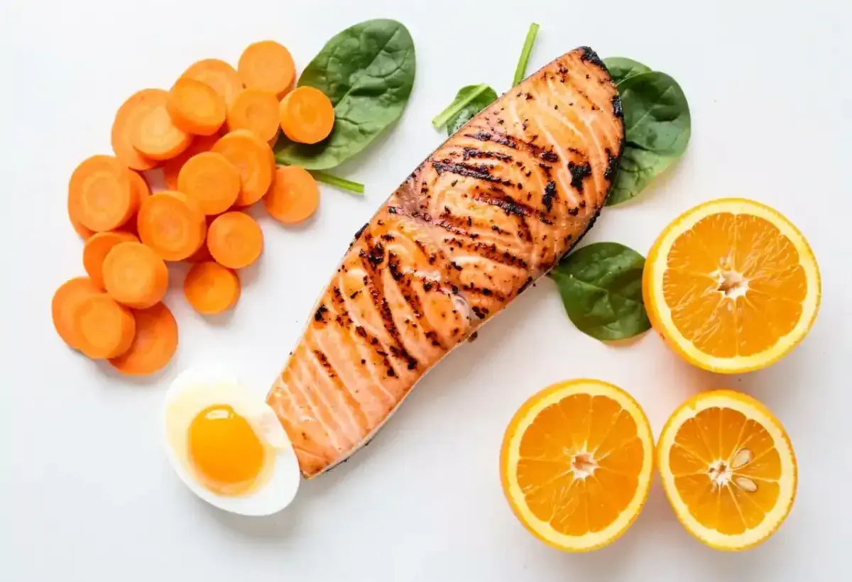 Colorful flatlay of carrots, salmon, spinach, egg, and citrus for eye health