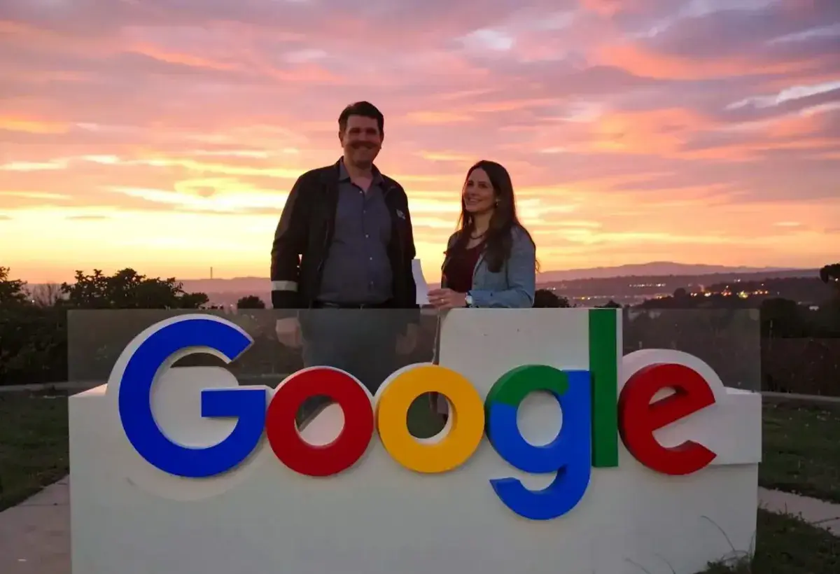 man and woman standing behind google logo with sunset background