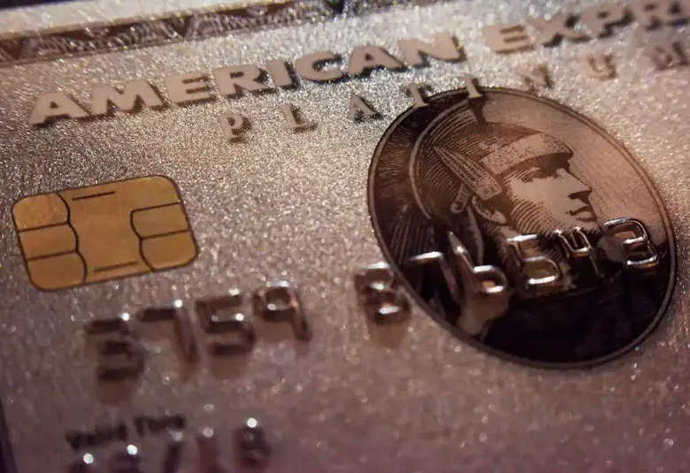Close-up of American Express Platinum and Gold cards fanned out on a dark marble surface