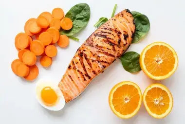Colorful flatlay of carrots, salmon, spinach, egg, and citrus for eye health