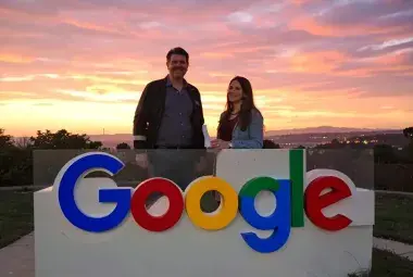 man and woman standing behind google logo with sunset background