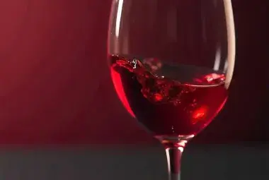 swirling red wine in clear glass on wooden table