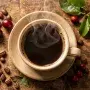 Steaming cup of coffee with fresh cherries and beans representing coffee's fruit origins